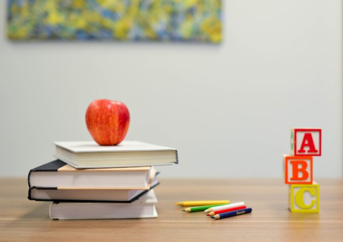 Apple on book pile, crayons, and a stack of ABC blocks